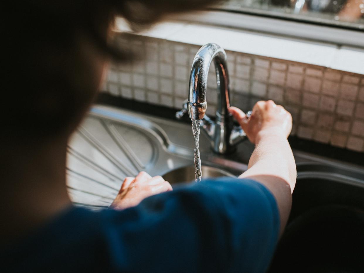 Person filling water bottle from sink faucet