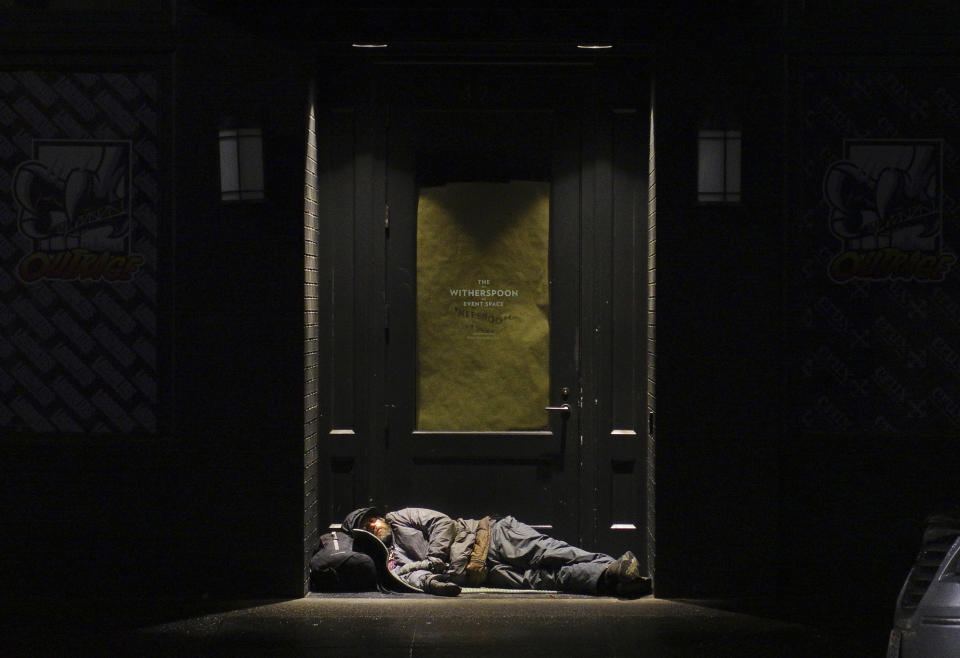 FILE - In this Sept. 19, 2017, file photo, a man sleeps in a doorway in downtown Portland, Ore. Voters in metropolitan Portland will be asked Tuesday, May 19, 2020 to approve taxes on personal income and business profits that would raise $2.5 billion over a decade to fight homelessness even as Oregon grapples with the coronavirus pandemic and its worst recession in decades. (AP Photo/Ted S. Warren, File)