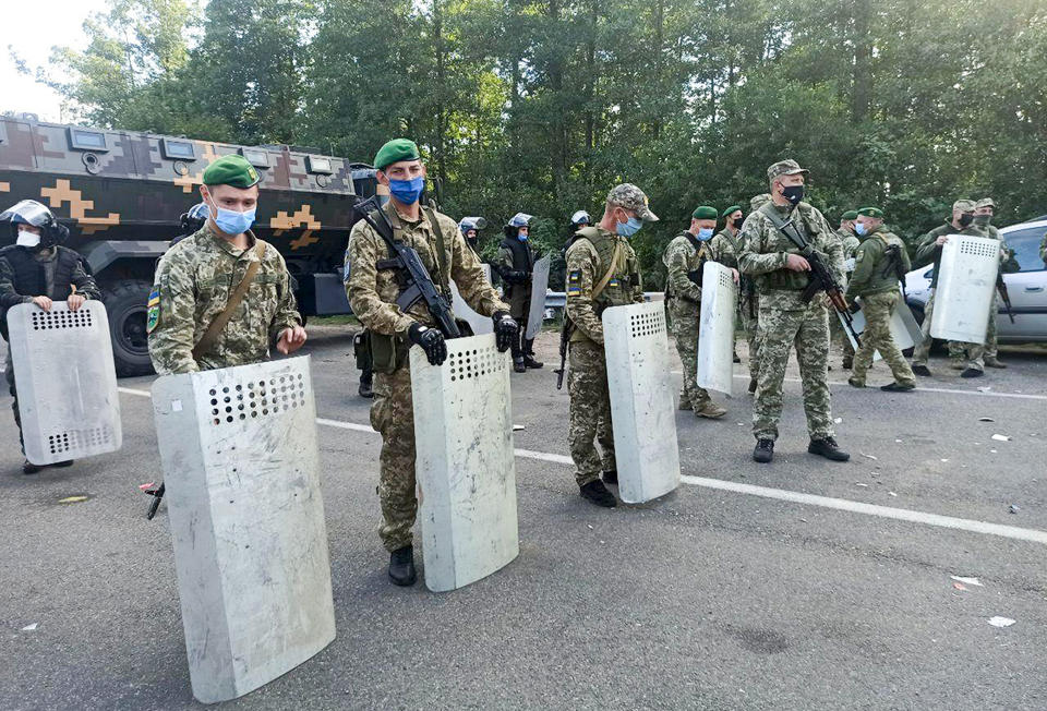 Ukrainian border guards block the road on the Belarus-Ukraine border, in Belarus, Tuesday, Sept. 15, 2020. About 700 Jewish pilgrims are stuck on Belarus' border due to coroavirus restrictions that bar them from entering Ukraine. Thousands of pilgrims visit the city each September for Rosh Hashana, the Jewish new year. However, Ukraine closed its borders in late August amid a surge in COVID-19 infections. (TUT.by via AP)