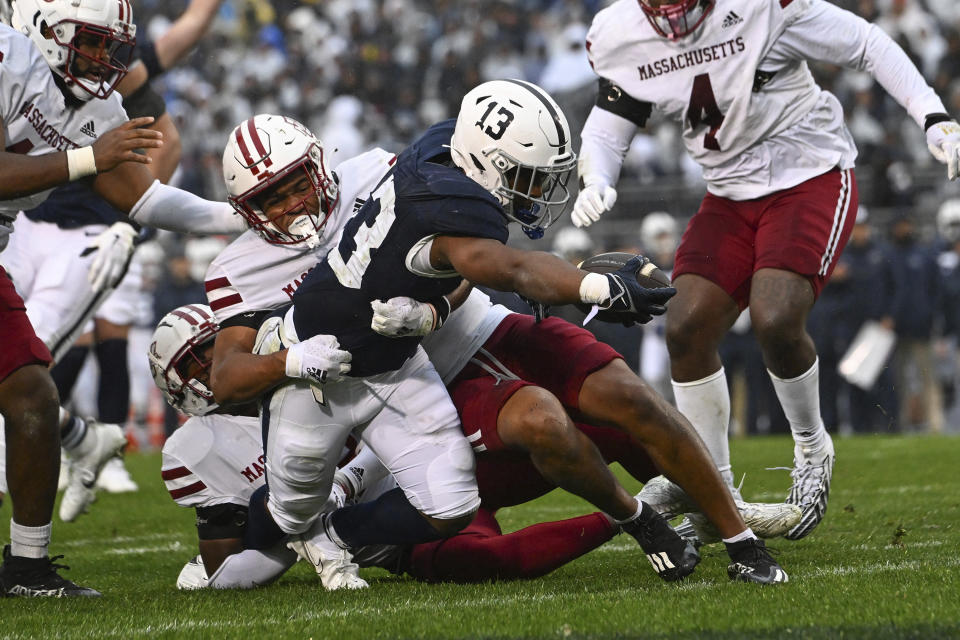 Penn State running back Kaytron Allen (13) dives past Massachusetts linebacker Nahji Logan (11) to score a touchdown during the first half of an NCAA college football game against Massachusetts, Saturday, Oct. 14, 2023, in State College, Pa. (AP Photo/Barry Reeger)