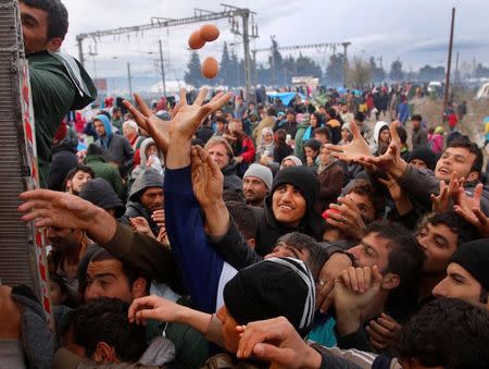 Migrants try to get products from a truck at a makeshift camp on the Greek-Macedonian border near the village of Idomeni, Greece March 10, 2016. REUTERS/Stoyan Nenov