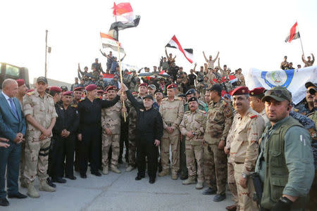 Iraqi Prime Minister Haider al-Abadi (C) holds an Iraqi flag as he announces victory over Islamic State in Mosul, Iraq, July 10, 2017. Iraqi Prime Minister Media Office/Handout via REUTERS