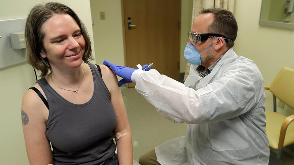 Jennifer Haller, left, smiles as the needle is withdrawn after she was given the first-stage safety study clinical trial of a potential vaccine for COVID-19. Source: AP