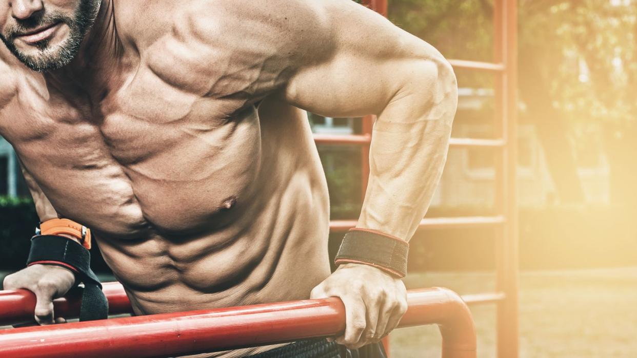 midsection of muscular man exercising at park