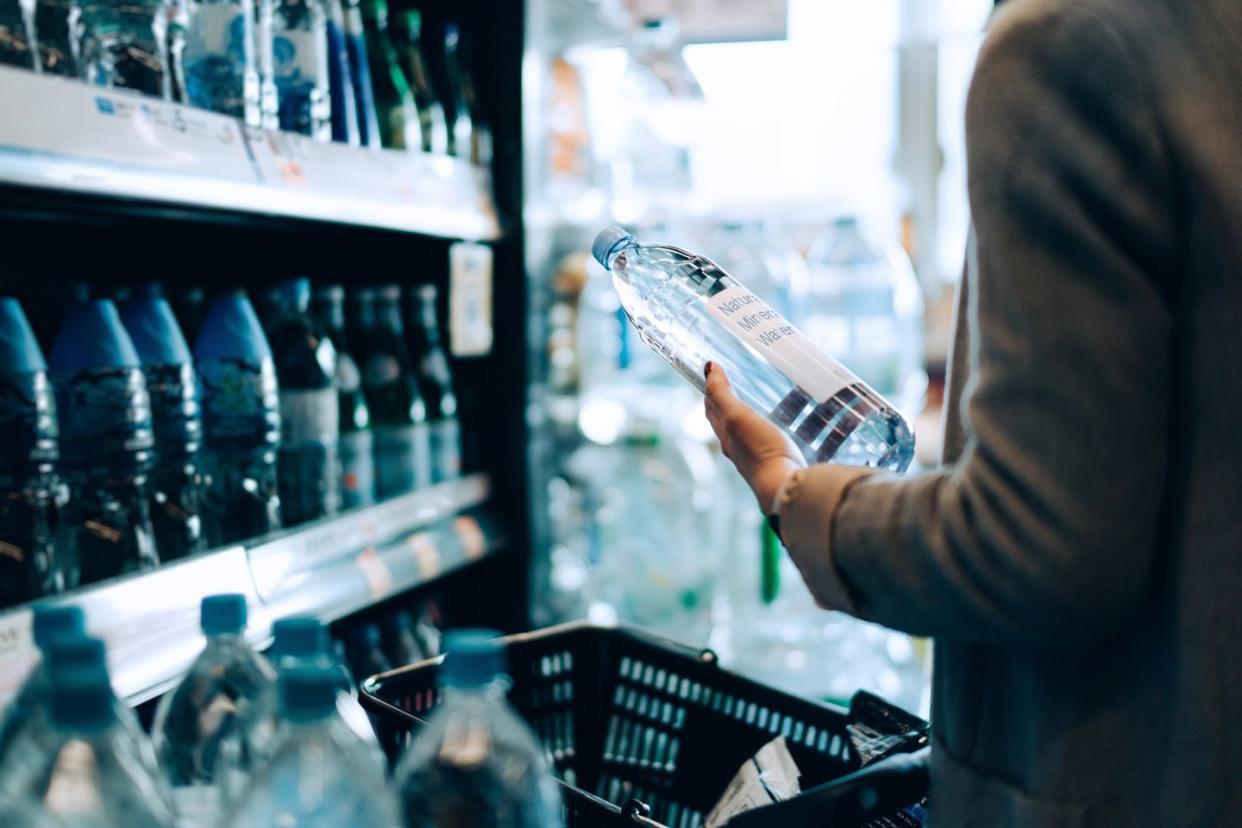 close up of woman with shopping cart shopping for bottled water along the beverage aisle in a supermarket healthy eating lifestyle