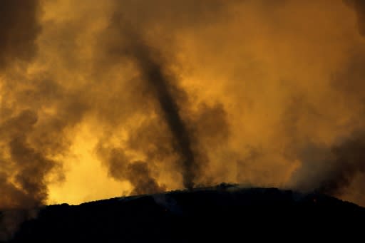 A whirlwind of ash rises from a ridge at a fire near Lake Elsinore in southern California