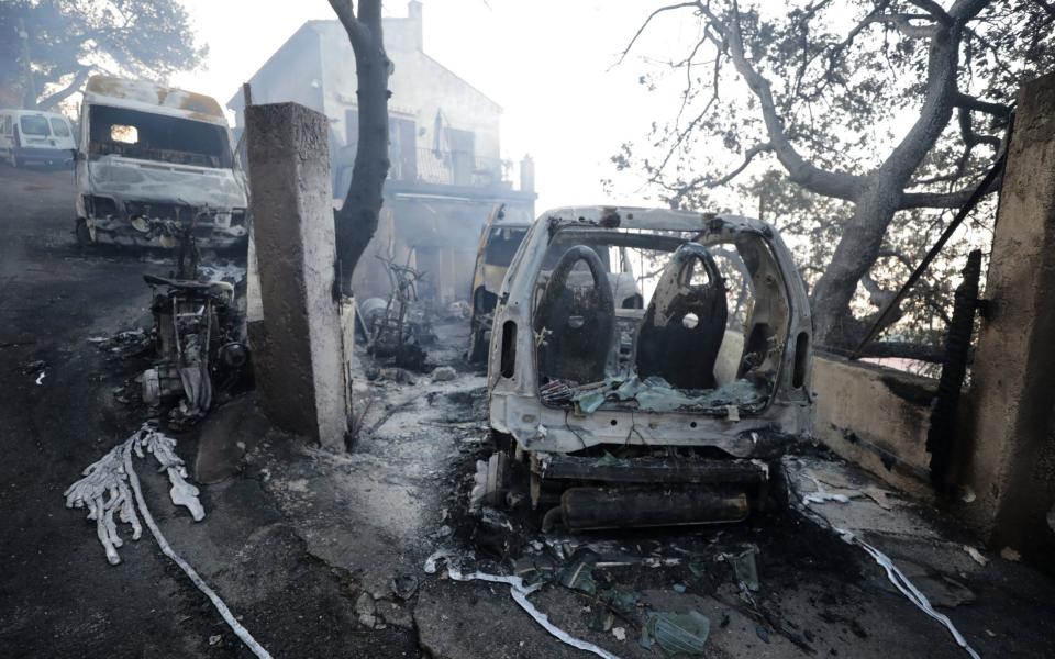 Vehicles that were destroyed by a burning wildfire are seen near a damaged home in Carros, near Nice - Credit: Reuters