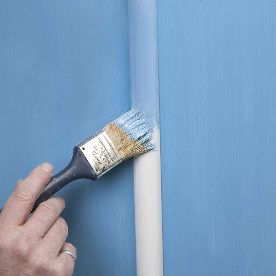 Person painting cable raceway blue to match a blue wall