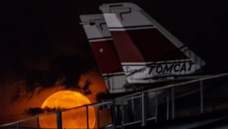 The flower moon sets behind Grumman F-14 Tomcat fighter jets at the Intrepid Museum, Thursday, May 23, 2024, in New York. The flower moon gets its name for appearing in late May — along with flowers and the blooming of new life.