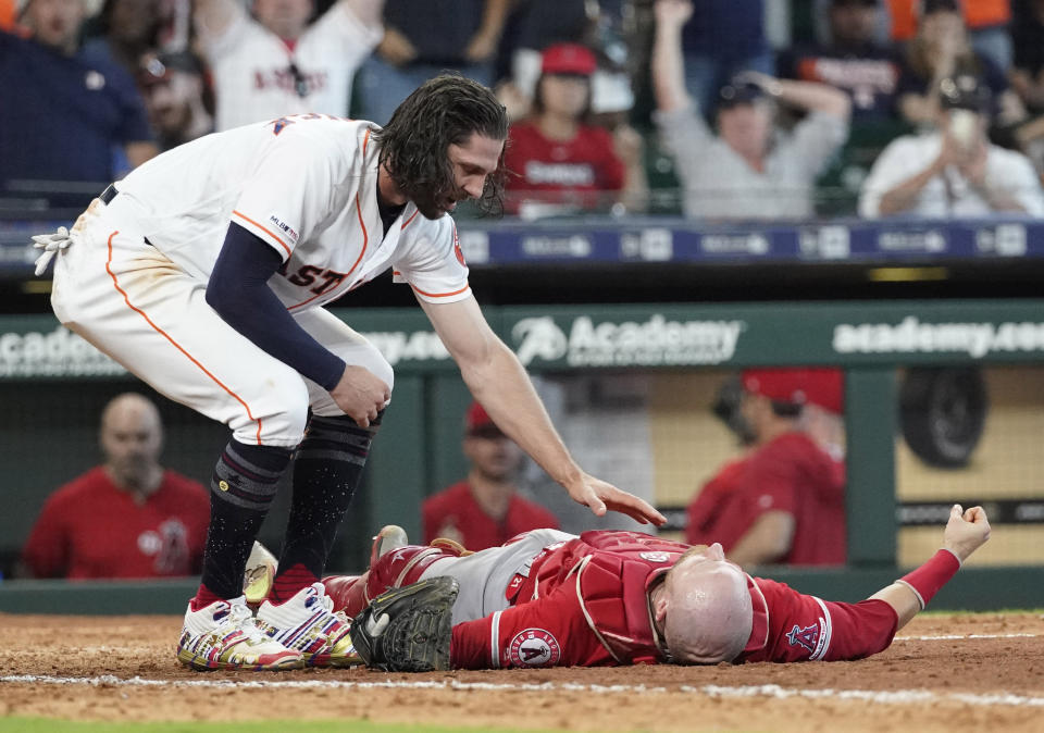 Houston Astros' Jake Marisnick, left, checks on Los Angeles Angels catcher Jonathan Lucroy after they collided at home plate during the eighth inning of a baseball game Sunday, July 7, 2019, in Houston. Marisnick was called out under the home plate collision rule. Lucroy was carted off the field. (AP Photo/David J. Phillip)