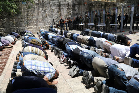 Palestinians pray as Israeli police officers look on by newly installed metal detectors at an entrance to the compound known to Muslims as Noble Sanctuary and to Jews as Temple Mount in Jerusalem's Old City July 16, 2017. REUTERS/Ammar Awad