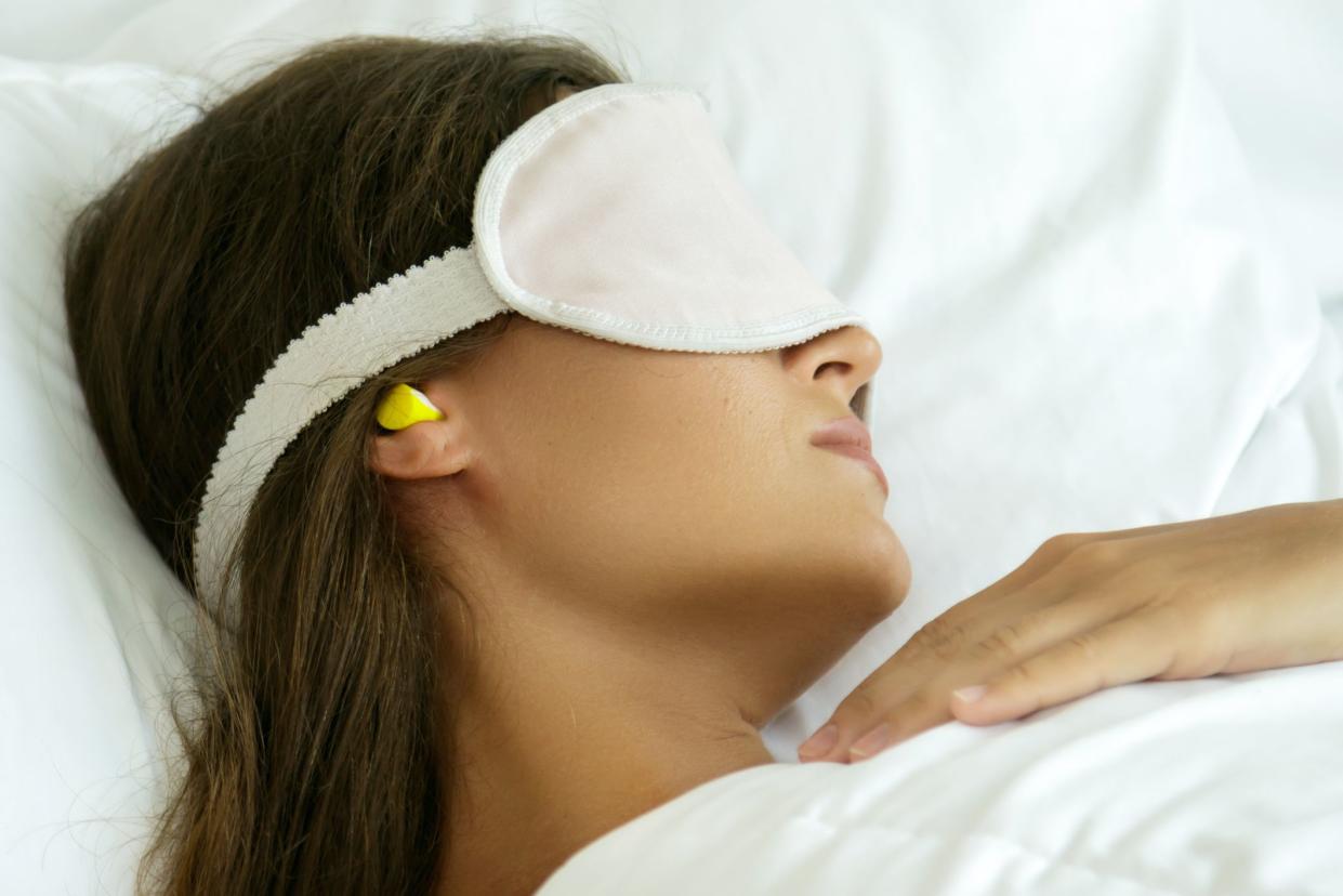 Woman is wearing eye mask and using earplugs for better sleeping