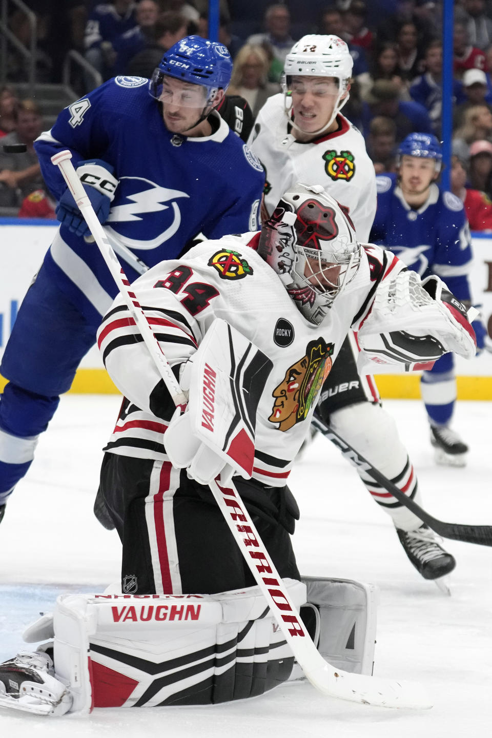 Chicago Blackhawks goaltender Petr Mrazek (34) makes a save as Tampa Bay Lightning left wing Tanner Jeannot (84) looks for a rebound with defenseman Alex Vlasic (72) during the second period of an NHL hockey game Thursday, Nov. 9, 2023, in Tampa, Fla. (AP Photo/Chris O'Meara)