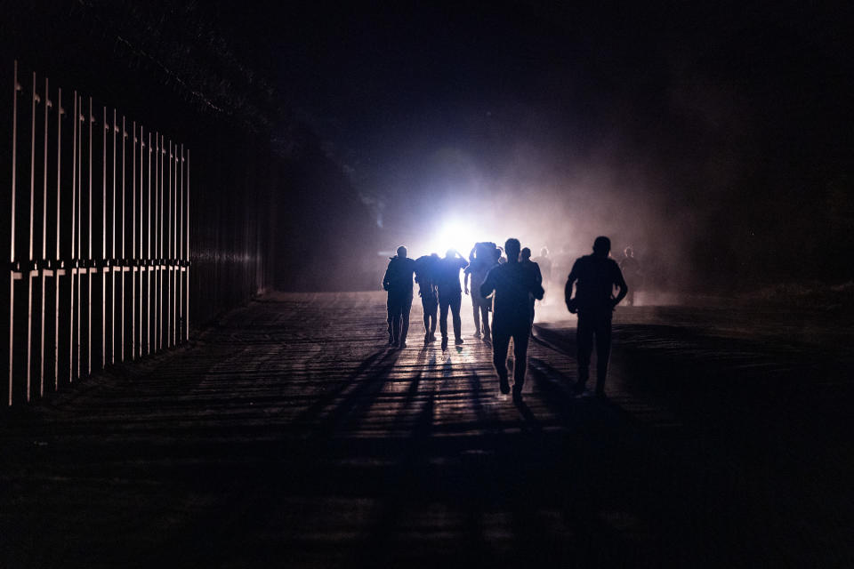 Migrantes caminan a lo largo de la valla fronteriza después de cruzar a Estados Unidos desde México a través de un ferrocarril abandonado el 23 de junio de 2024 en Jacumba Hot Springs, San Diego, California. (Foto de Qian Weizhong/VCG vía Getty Images)