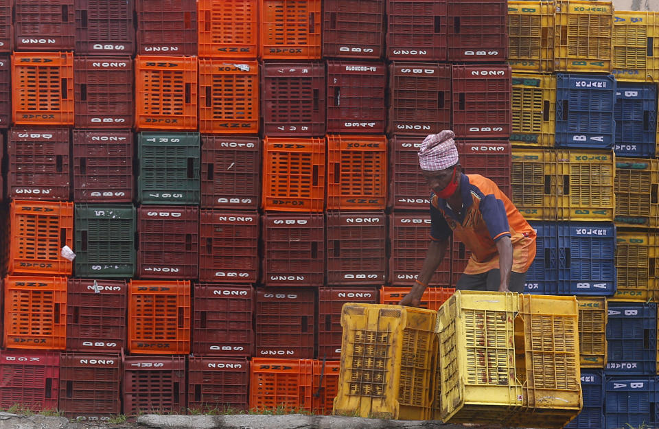 A worker sorts baskets at wholesale market in Mumbai, India, Tuesday, June 15, 2021. (AP Photo/Rafiq Maqbool)