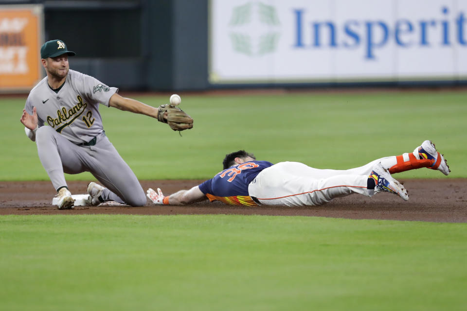 Oakland Athletics shortstop Max Schuemann, left, misses the throw aws Houston Astros' Kyle Tucker, right, slides in with an RBI double during the first inning of a baseball game Wednesday, May 15, 2024, in Houston. (AP Photo/Michael Wyke)