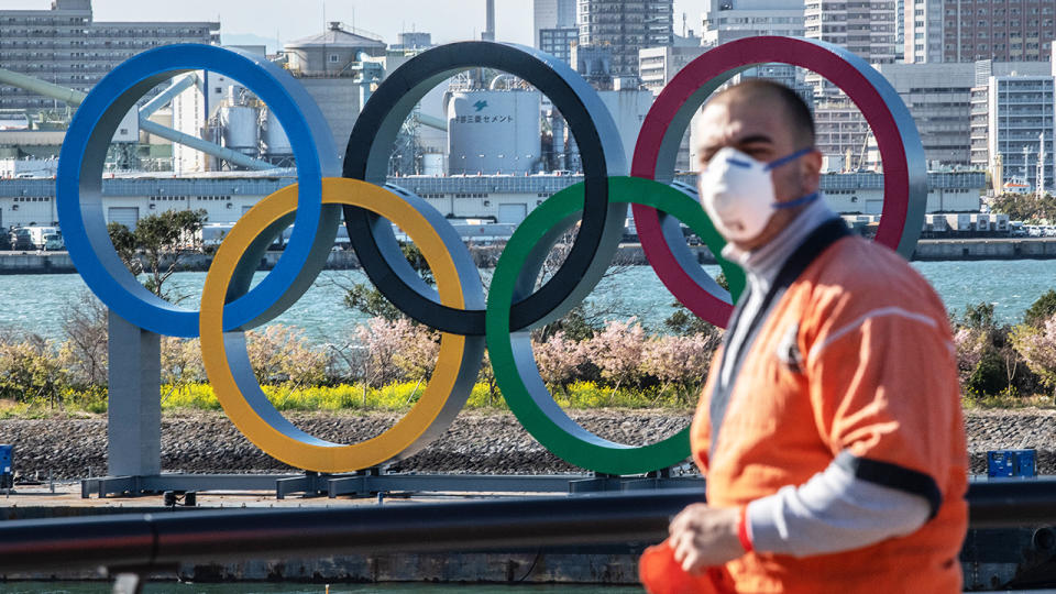 A man wearing a face mask, pictured here walking near the Olympic Rings in Tokyo, Japan.