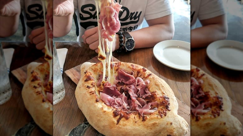 person eating prosciutto cheese boat