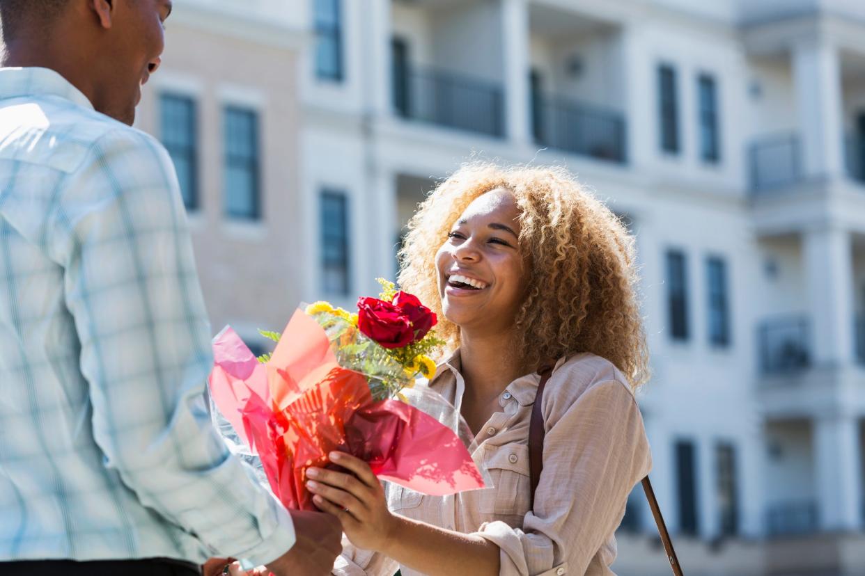 Young man gives flowers to girlfriend