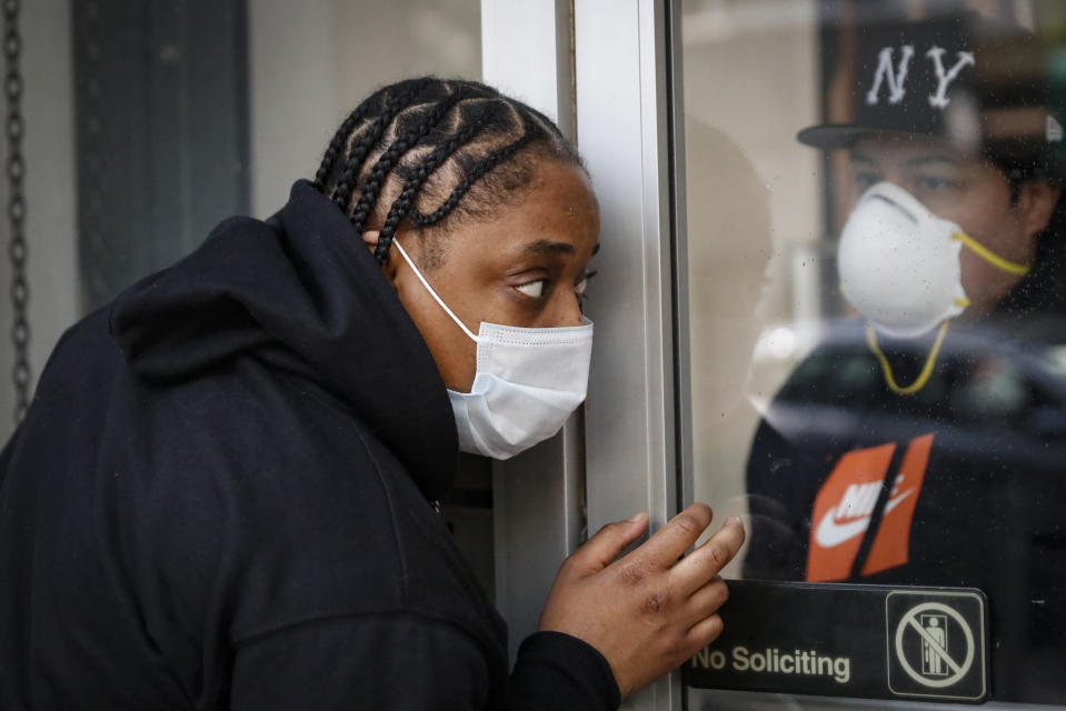 Roni Colvert attempts to make purchases from curb-side at The Loop fashion and shoe store as businesses slowly begin to reopen after social distancing restrictions shuttered storefronts nationwide, Tuesday, May 26, 2020, in Yonkers, N.Y. (AP Photo/John Minchillo)