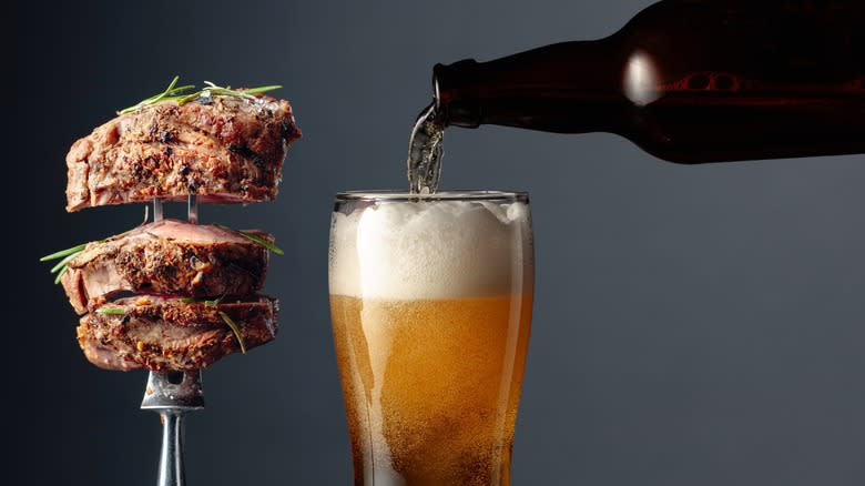 Meat on a fork next to beer poured into glass