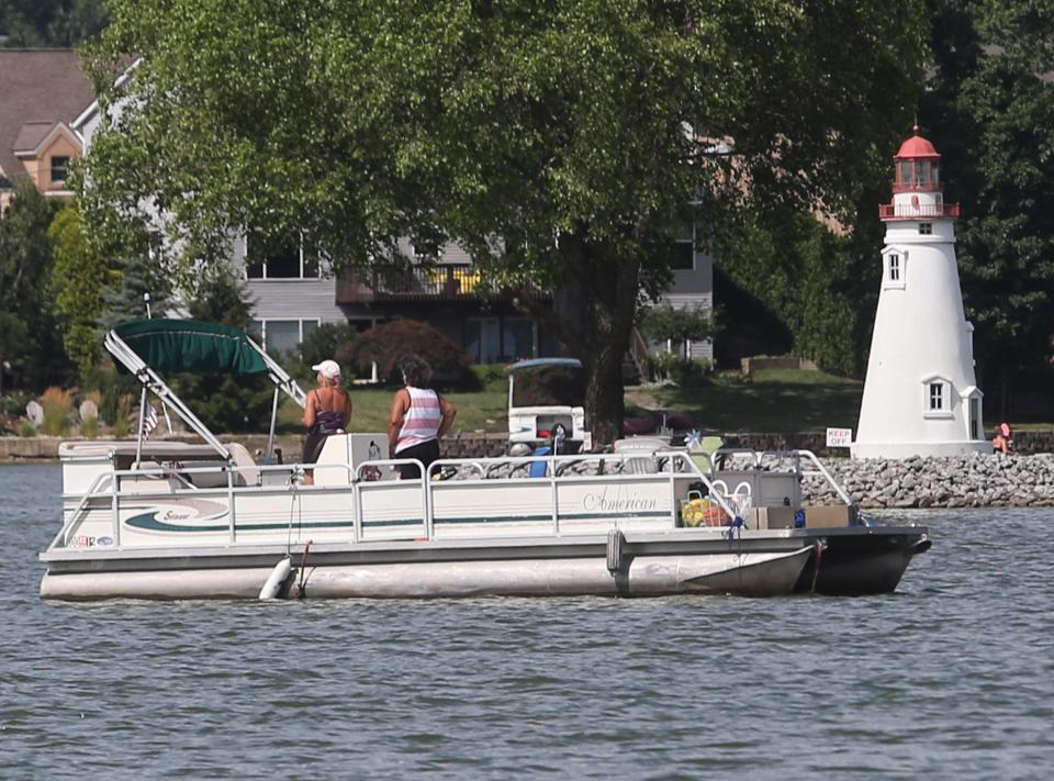 Boaters pass a lighthouse on Lake Cable in Jackson Township on Monday, July 25, 2022.