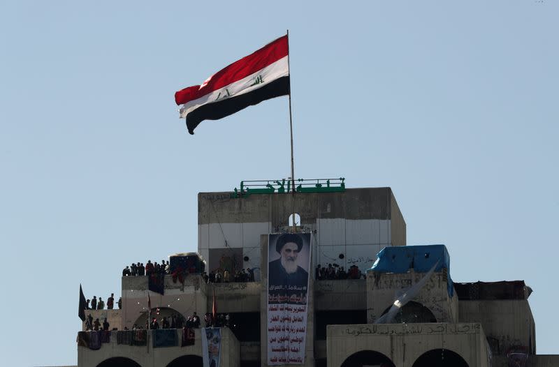 Iraqi demonstrators stand at the high-rise building, called by Iraqi the Turkish Restaurant Building, during ongoing anti-government protests in Baghdad