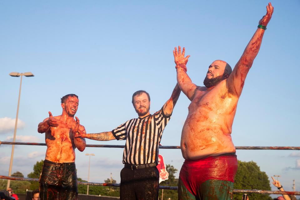 Dustin Stanford from Hometown BBQ, right, is declared the winner of the match as his opponent Jesse Parsons from Sow Luau, left, claps for him while competing in sauce wrestling during the Memphis in May World Championship Barbecue Cooking Contest on May 15, 2024, at Liberty Park in Memphis. Nephew of team cofounding member, Noel Grafe, Stanford defended his 2023 victory with another sauce wrestling belt this year.