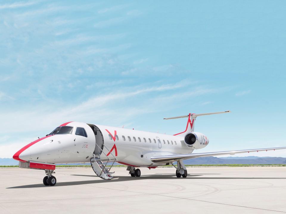 A JetSuiteX aircraft on a concrete runway with a clear blue sky above.