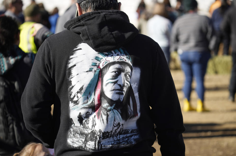 A participant wears a hoodie with a drawing as city officials and other partners watch the transfer of 35 Denver Mountain Park bison to representatives of four Native American tribes and one memorial council as they reintroduce the animals to tribal lands Wednesday, March 15, 2023, near Golden, Colo. (AP Photo/David Zalubowski)