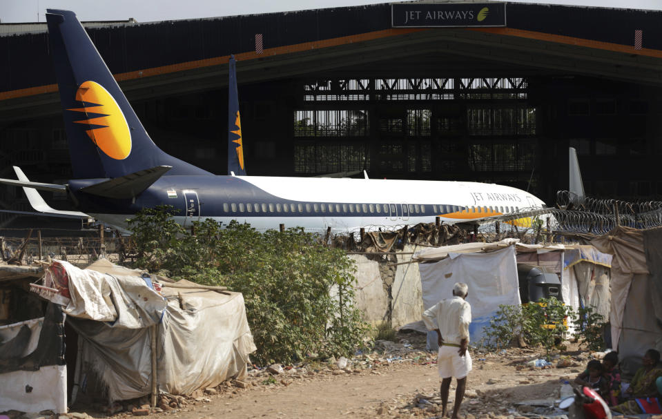 A man stands next to his shanty as Jet Airways aircraft is seen parked at a hanger at Chhatrapati Shivaji Maharaj International Airport in Mumbai, Monday, March 25, 2019. The chairman of India’s private Jet Airways has quit amid mounting financial woes forcing the airline to suspend operations on 14 international routes with more than 80 planes grounded. (AP Photo/Rafiq Maqbool)