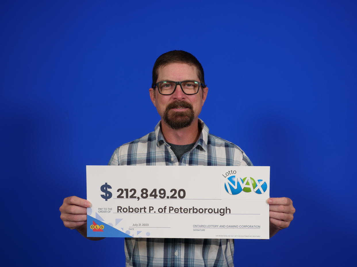 Man holding a $212,849.20 Lotto Max check. 