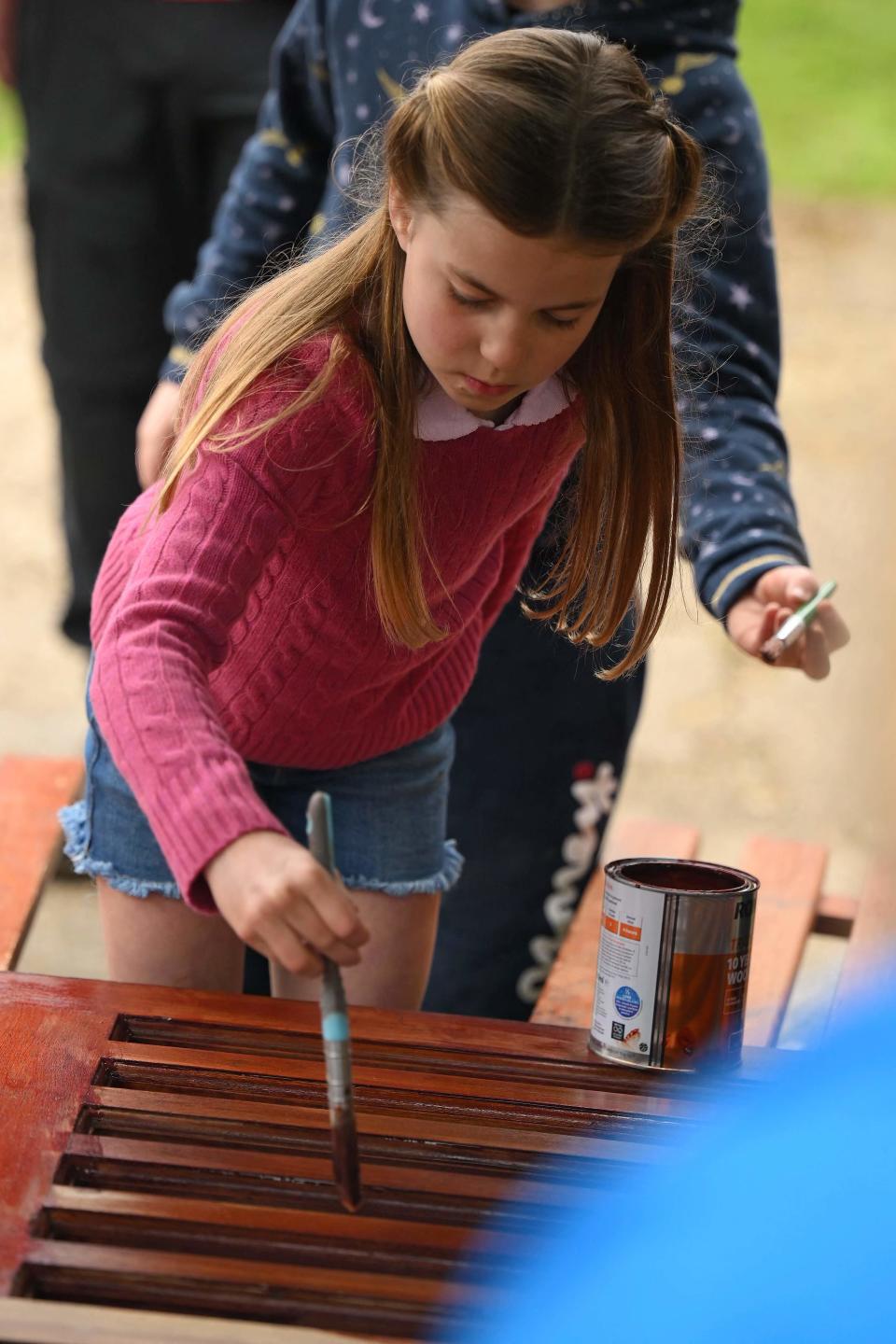 Princess Charlotte stains wood while taking part in the Big Help Out.