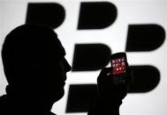 A man is silhouetted against a video screen with the Blackberry logo as he pose with a Blackberry Q10 in this photo illustration taken in the central Bosnian town of Zenica, September 21, 2013. REUTERS/Dado Ruvic