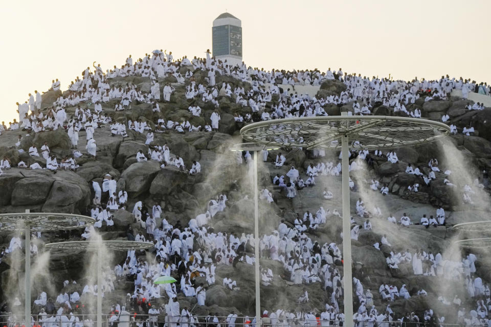 Water mist is sprayed on Muslim pilgrims as they pray on the rocky hill known as the Mountain of Mercy, on the Plain of Arafat, during the annual Hajj pilgrimage, near the holy city of Mecca, Saudi Arabia, Tuesday, June 27, 2023. Around two million pilgrims are converging on Saudi Arabia's holy city of Mecca for the largest Hajj since the coronavirus pandemic severely curtailed access to one of Islam's five pillars. (AP Photo/Amr Nabil)