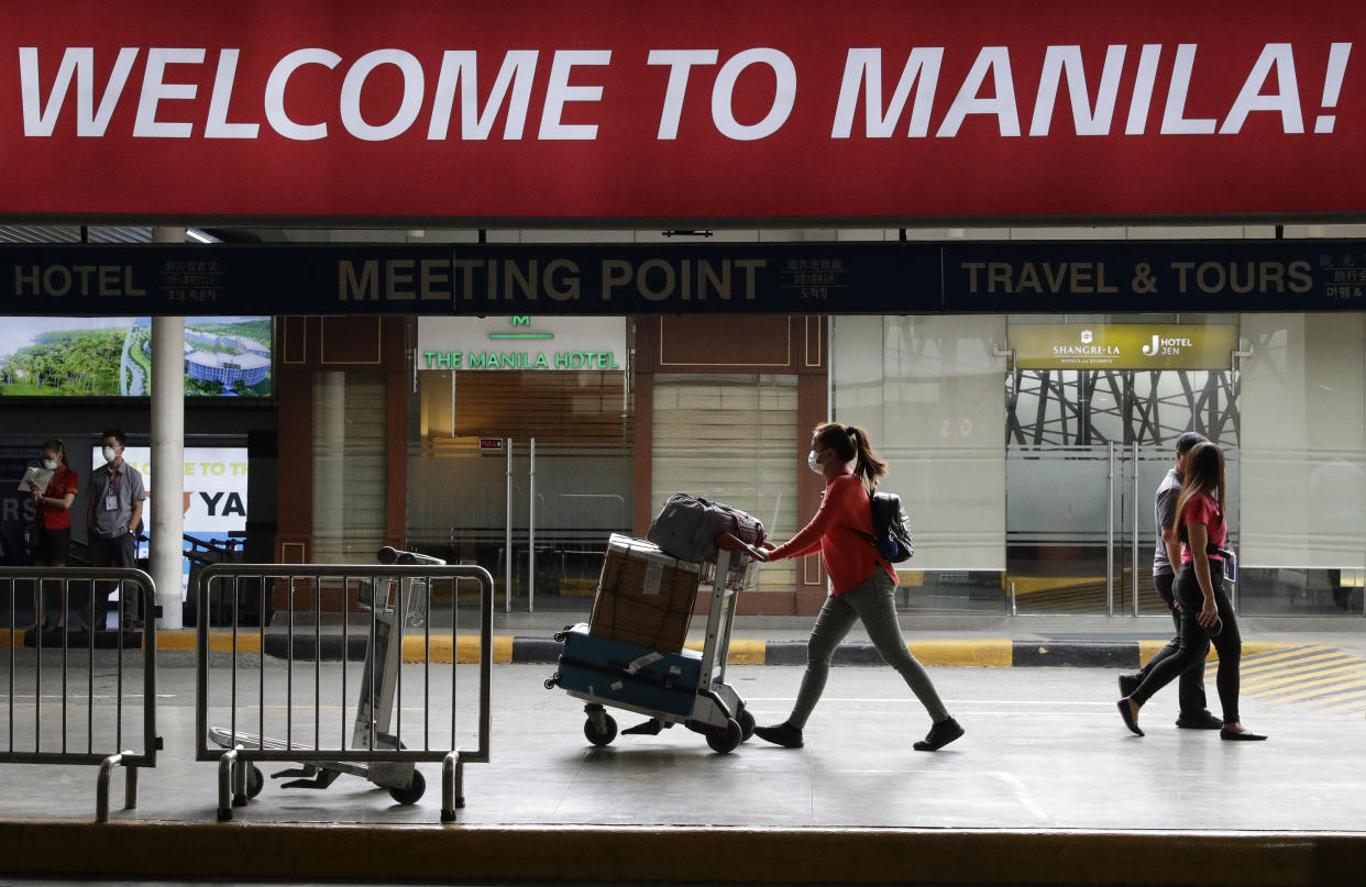 FILE PHOTO: A woman wearing a protective face mask arrives at the Manila's international airport, Philippines on Monday Feb. 3, 2020. (AP Photo/Aaron Favila)