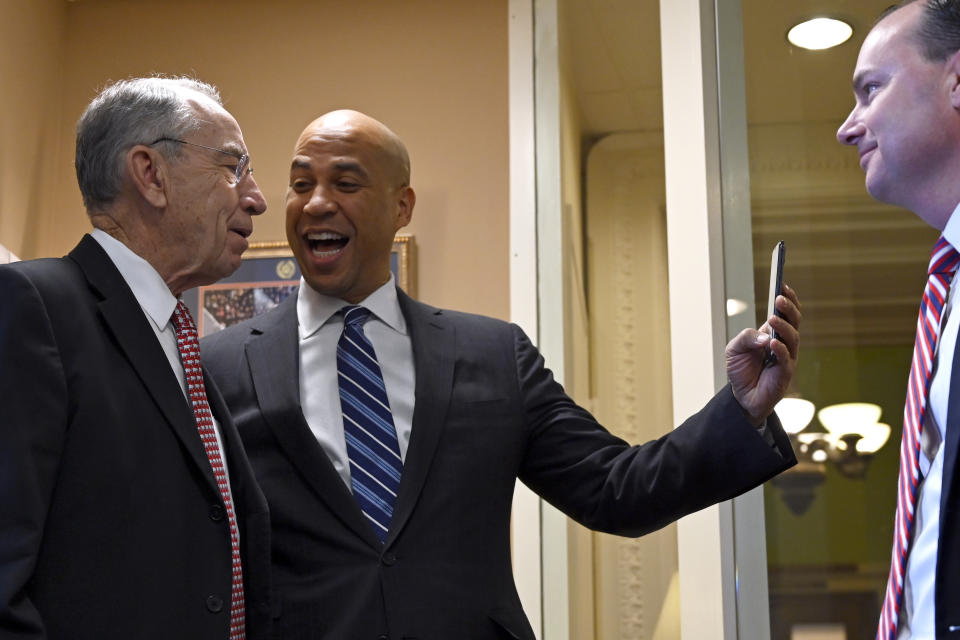 Sen. Cory Booker, D-N.J., center, joins Sen. Chuck Grassley, R-Iowa, left, in a Instagram Live post as Sen. Mike Lee, R-Utah, right, watches before they participate in a news conference on Capitol Hill in Washington, Wednesday, Dec. 19, 2018, on prison reform legislation. A criminal justice bill passed in the Senate gives judges more discretion when sentencing some drug offenders and boosts prisoner rehabilitation efforts. (AP Photo/Susan Walsh)