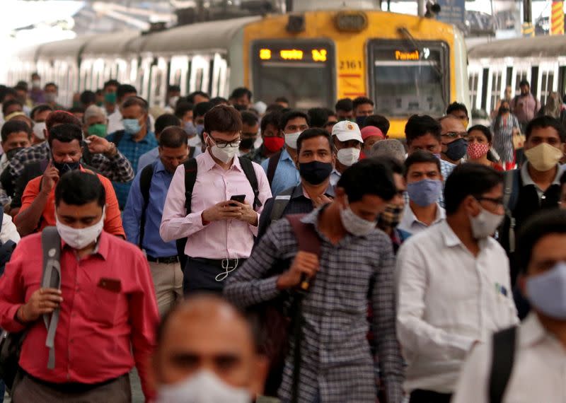 People wearing protective masks walk on a platform at the Chhatrapati Shivaji Terminus railway station, in Mumbai