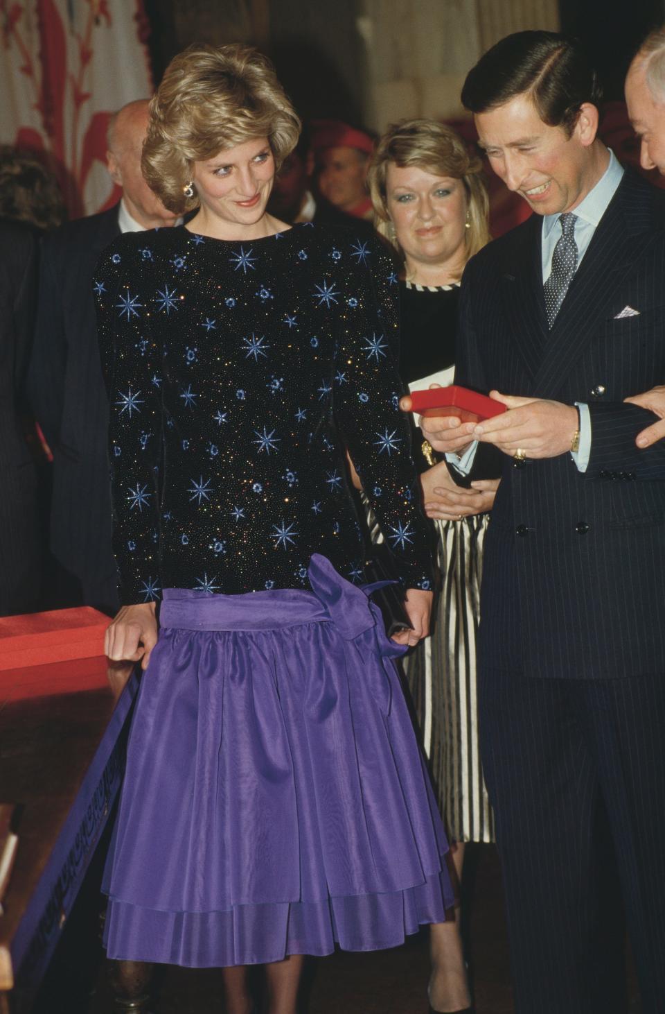 Princess Diana looks at Prince Charles while wearing a blue dress in 1985.