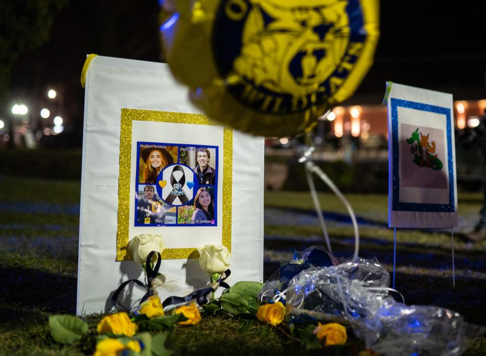 Photos of the victims of an active shooter at Oxford High School are shown with flowers during a candlelight vigil at Children's Park in Lake Orion on December 2, 2021.