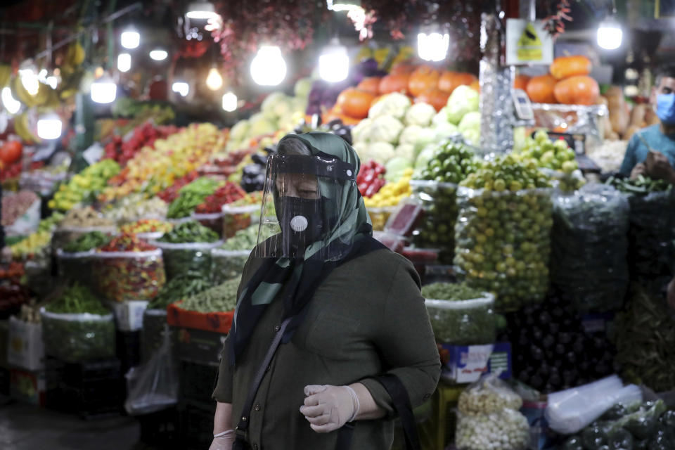 A woman wearing a protective face mask and gloves to help prevent the spread of the coronavirus walks through the Tajrish traditional bazaar in northern Tehran, Iran, Thursday, Oct. 15, 2020. Eight months after the pandemic first stormed Iran, pummeling its already weakened economy and sickening officials at the highest levels of its government, authorities appear just as helpless to prevent its spread. (AP Photo/Ebrahim Noroozi)