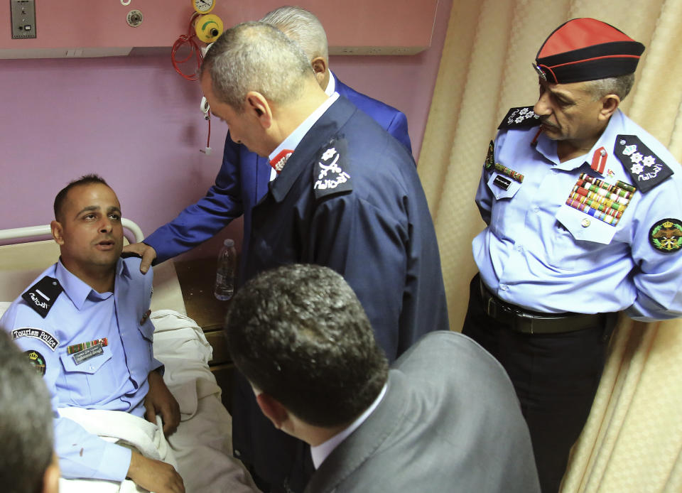 CORRECTS LOCATION OF HOSPITAL TO JERAASH - Royal Court chief Yousef Issawi, right, visits one of the victims of a knife attack in Jeraash, Jordan on Wednesday, Nov. 6, 2019. A young man from a Palestinian refugee camp on Wednesday stabbed eight people, including four foreign tourists and their tour guide, at a popular archaeological site in Jeraash, in northern Jordan, security officials said. The wounded included three Mexican tourists and a Swiss woman, according to Jordan's Public Security office. Along with the tour guide, three other Jordanians, including two security officers and a bus driver, were also hurt before the attacker was subdued and arrested. (AP Photo/Raad Adayleh)