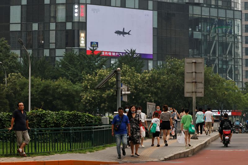 FOTO DE ARCHIVO. Los peatones pasan por delante de una pantalla gigante que emite un informe de noticias sobre los ejercicios militares del Ejército Popular de Liberación (EPL) chino en torno a Taiwán, en Pekín, China