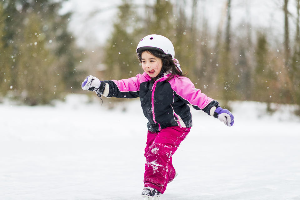 Preschool aged child playing in the snow with a helmet for winter safety