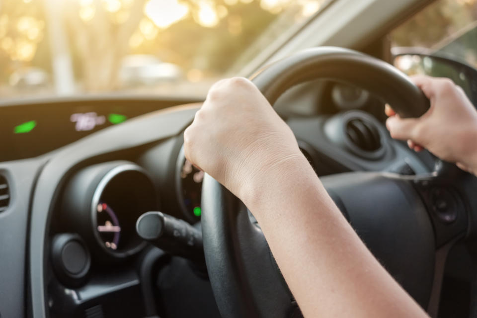 A woman's hands seen on a steering wheel.