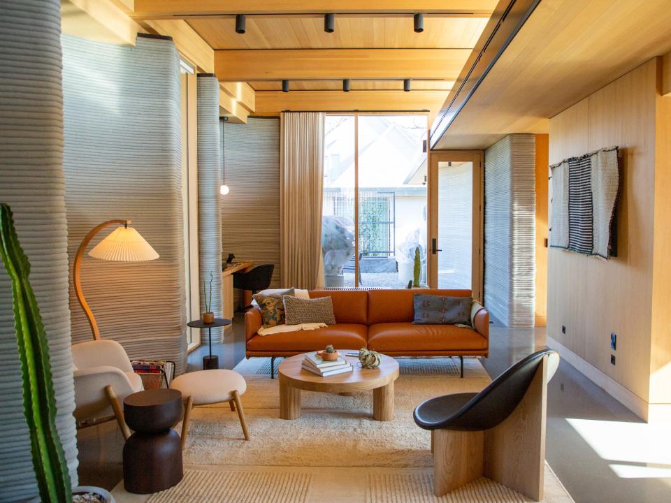 Inside Icon's over 2,000-square-foot House Zero in Austin. There's a lounge chair with a floor lamp surrounded by other furniture like a couch, coffee table, and another lounge chair.