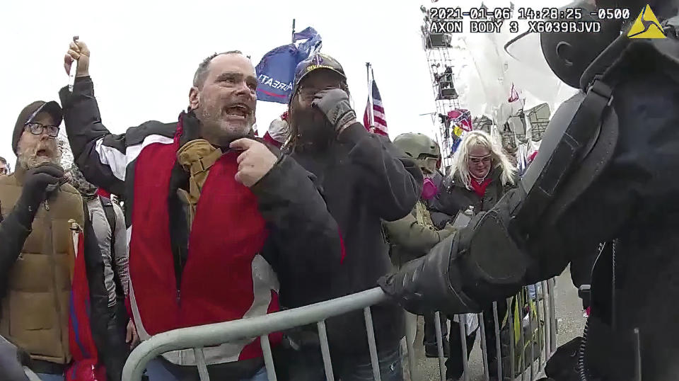 This still frame from Metropolitan Police Department body worn camera video shows Thomas Webster, in red jacket, at a barricade line at on the west front of the U.S. Capitol on Jan. 6, 2021, in Washington. Webster, a Marine Corps veteran and retired New York City Police Department Officer, is accused of assaulting an MPD officer with a flagpole. A number of law enforcement officers were assaulted while attempting to prevent rioters from entering the U.S. Capitol. (Metropolitan Police Department via AP)