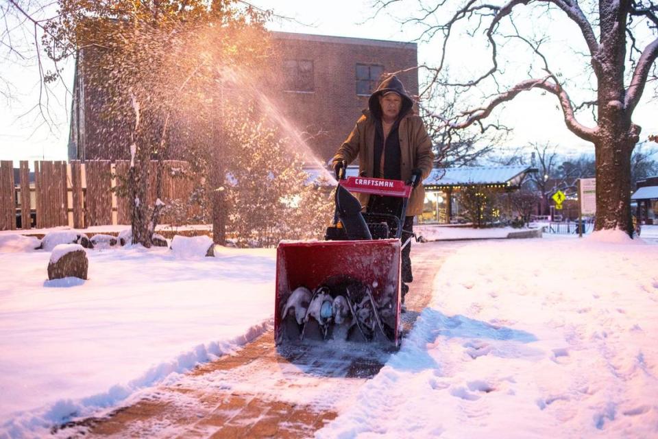 Jose Rodriguez clears a sidewalk leading to the parking lot from Weaver Street Market in Carrboro, N.C. on Saturday morning, Jan. 22, 2022.