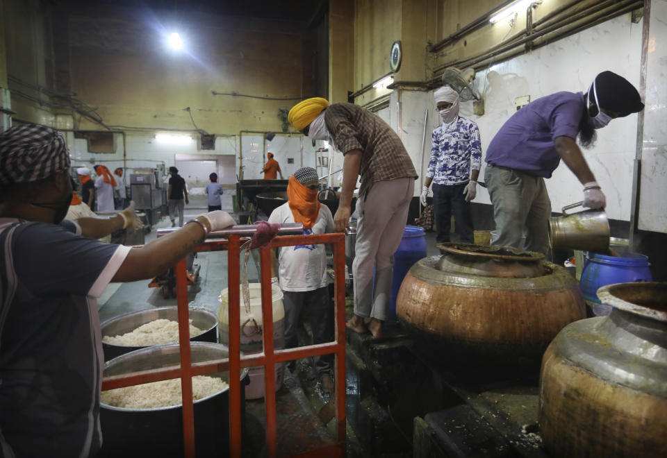 FILE - In this May 10, 2020, file photo, Sikh volunteers load prepared food onto a trolley to be taken out from the kitchen hall of the Bangla Sahib Gurdwara in New Delhi, India. An act of generosity or self-sacrifice. A whimsical gesture to distract neighbors from anxiety or cabin fever. In India, which ordered one of the world’s strictest lockdowns, feeding the working poor at a time they couldn’t work was an obvious concern. The Sikh temple Bangla Sahib Gurdwara in New Delhi rose to the challenge, ramping up a kitchen operation that already fed a half-million people per week to help the growing ranks of the unfortunate. (AP Photo/Manish Swarup, File)