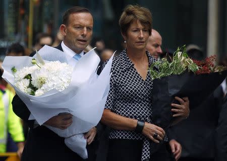 Australian Prime Minister Tony Abbott and his wife Margie prepare to place floral tributes near the cafe in central Sydney December 16, 2014. REUTERS/David Gray